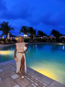 Woman wearing a white resort outfit by a pool in Turks and Caicos at night